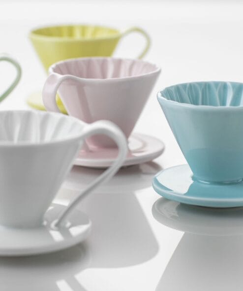 Cafec Flower Dripper Flower Dripper merkezden dışarıya su sirkülasyonu sağlayıp filtreleme yapacak şekilde tasarlanmıştır. Fincana istenmeyen tatların geçmesini önlemek için hızlı ve pürüzsüz su akışı gereklidir. Bunu sağlamak için uzun süren araştırmalardan sonra Cafec, dripper içinde gördüğünüz çiçek şekilli ideal tasarıma ulaşmıştır! Flower Dripper adını bu tasarımdan alıyor. Bu dizayn sayesinde döküş ve çıkış arasındaki su akış oranları eşit tutulabilir ve suyun dripper içinde birikmesine engel olunur. Doğru demlemeye estetik biçimde ulaşmanın en zarif yolu!  Stabil, hızlı ve dengeli demlemer için Flower Dripper’ınızı tüm Cafec filtrelerimiz ile kullanabilirsiniz. Cafec Flower Dripper özellikleri Tek Delik Tabanın merkezinde yer alan tek ve büyük çıkış deliği derin bir filtreleme ve hızlı çıkış sağlar. Konik Şekil Konik şekilli tasarım derin bir filtreleme ve suyun dripper içinde sirkülasyonuna imkan sağlar. Bu sayede su tüm kahve partiküllerine yayılır ve kahveden almak istediğimiz gövde çıkarılırken pürüzsüz de bir sonuç elde edilir. Taban Tasarımı Taban deliği hatları kahve için tutarlı çıkış patikaları yaratarak dengeli bir akış ve fincan sonuçları sağlar. Arita Ware Nedir?  Arita Ware 400 yıllık tarihe sahip özel bir Japon porselenidir. Yüksek kaliteli porselen hamuru ve taş tozuyla bir karışım elde edilir ve bu karışım 1.300C sıcaklıkta işlenir. Sonuç mineral kadar sert olmasına rağmen zarif bir dokudur. Arita Ware tüm dünyada beğenilen en kaliteli Japon geleneksel porselenidir. Cafec Flower Dripper Cup yeşil